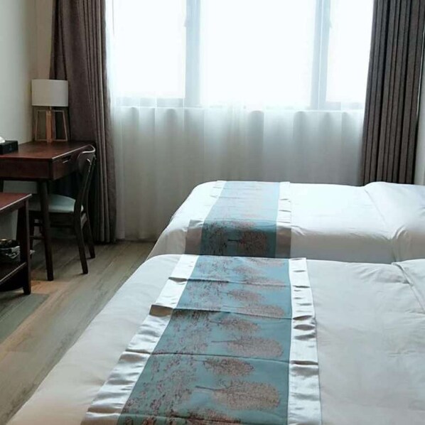 A hotel room with a bed, a desk, and a chair. - Poltton International Apartment Jinding (Shanwei)