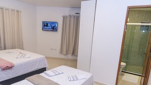 Camera d'albergo con due letti, televisione a parete e zona doccia.