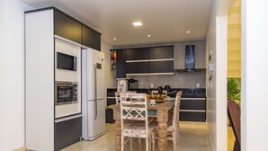 Una cucina compatta con elettrodomestici moderni, un'area pranzo con sedie diverse e un piccolo bancone con forno a microonde.