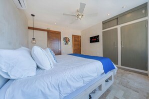 A bedroom with a bed, a ceiling fan, a TV, and a wardrobe.