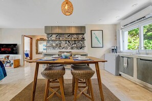 A modern kitchen with a dining area, featuring a large window, a built-in oven, and a television.