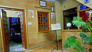 A room with a wooden door labeled '101', a window with a grid pattern, a music stand with sheet music, and a globe on a cabinet. - Blessing Hotel (Jaisalmer)