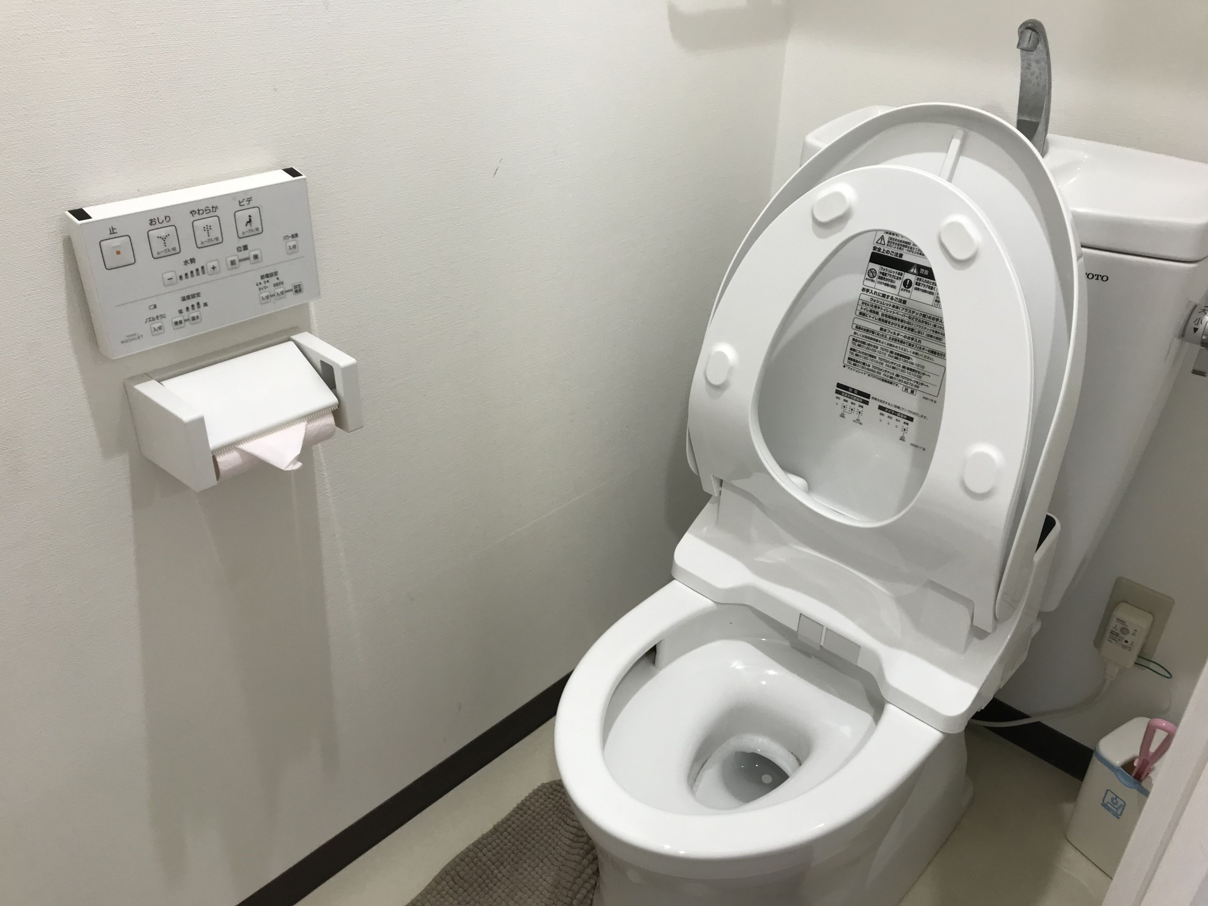A modern toilet with a control panel and a bidet attachment.