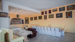 A dining area with multiple tables and chairs, a bar area with bottles, and artwork on the walls. - Hotel Tsiskari (Telavi)
