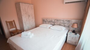 A neatly made bed with white linens, a wooden nightstand with a lamp, and a wooden wardrobe. - Hotel Tsiskari (Telavi)