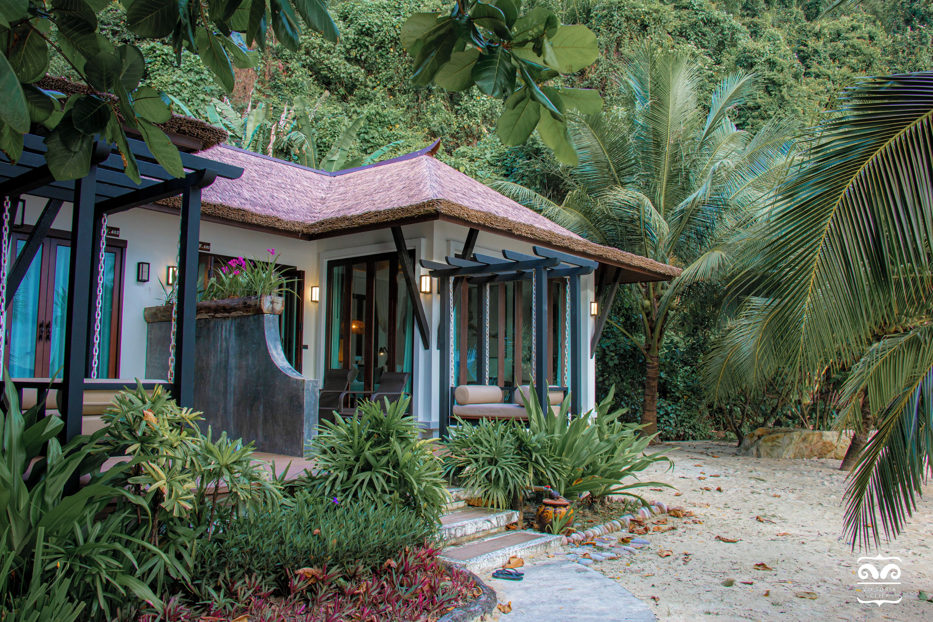 Une maison au toit de chaume, entourée d’une végétation tropicale luxuriante.
