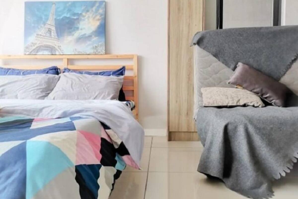 A bedroom with a bed, a couch, and a painting of the Eiffel Tower.