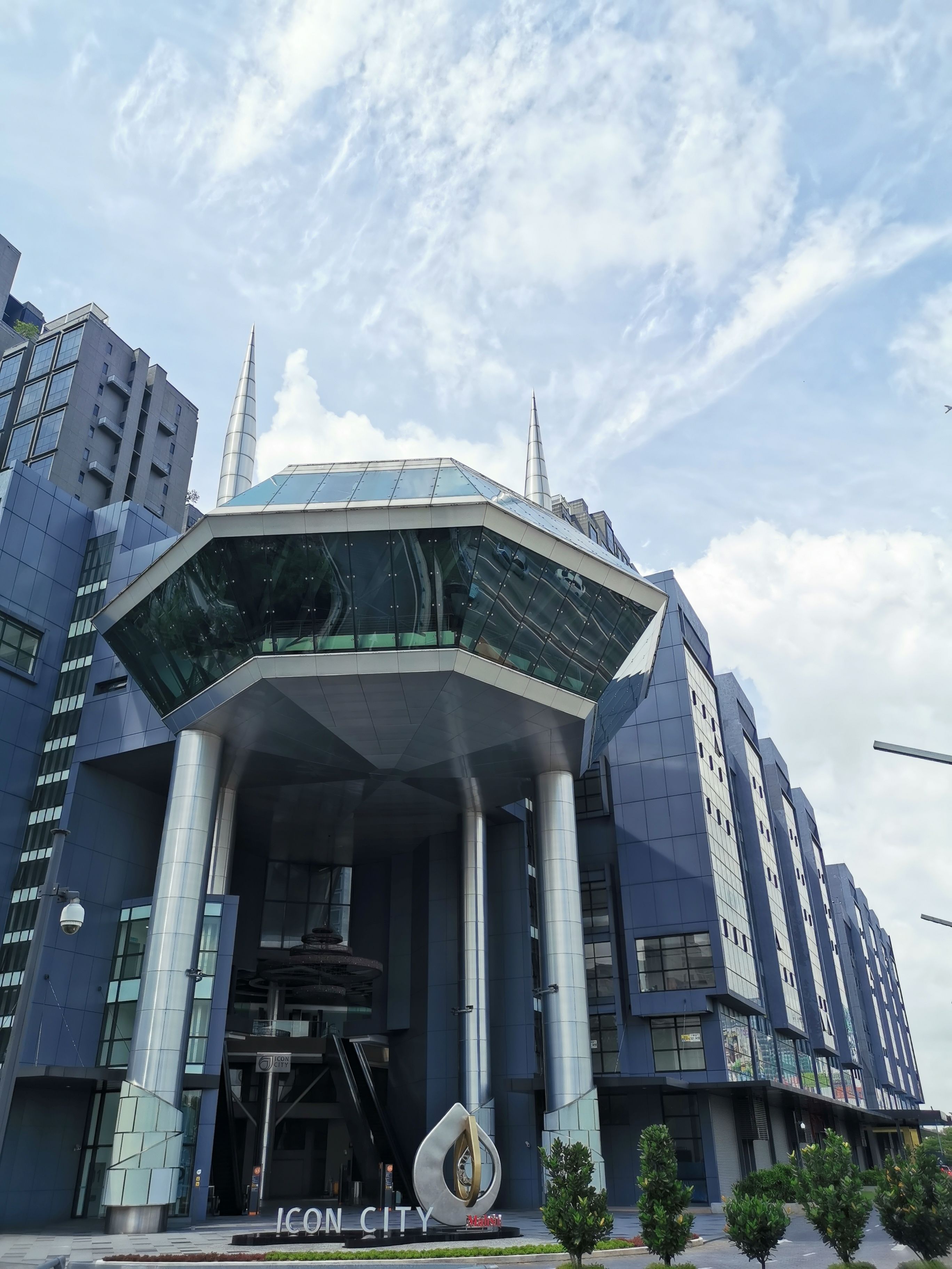 A modern building with a prominent glass entrance and a unique sculpture in front.