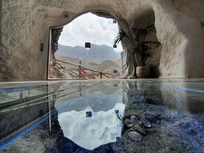 A reflective pool with a mountainous view, a potted plant, and a wooden structure.