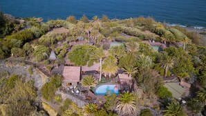 An aerial view of a coastal property with a swimming pool, multiple buildings, and lush vegetation. - Redondo de Guayedra (Agaete)