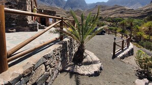 A stone building with a wooden staircase leading to a viewing platform. - Redondo de Guayedra (Agaete)