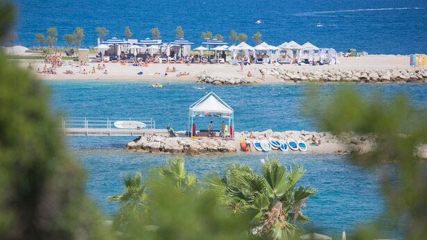 Un complexe hôtelier de bord de mer doté d’une piscine, de parasols et de chaises de plage.