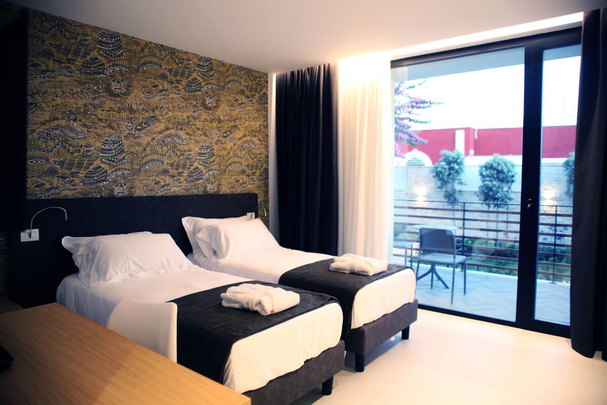 Une chambre d’hôtel avec deux lits, une grande fenêtre et une vue sur l’extérieur.