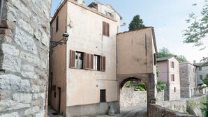 A narrow cobblestone street flanked by historic stone buildings with arched doorways and traditional shutters. - Spectacular Views  -  Charming House in Central Todi  (Todi)