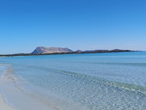 Una playa con aguas cristalinas y una montaña al fondo.