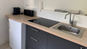 A compact kitchen with a modern design, featuring a built-in stove, a sink, and a small refrigerator.