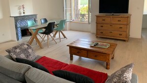 A living room with a sofa, coffee table, TV, wooden dresser, and a dining area with chairs and a table.