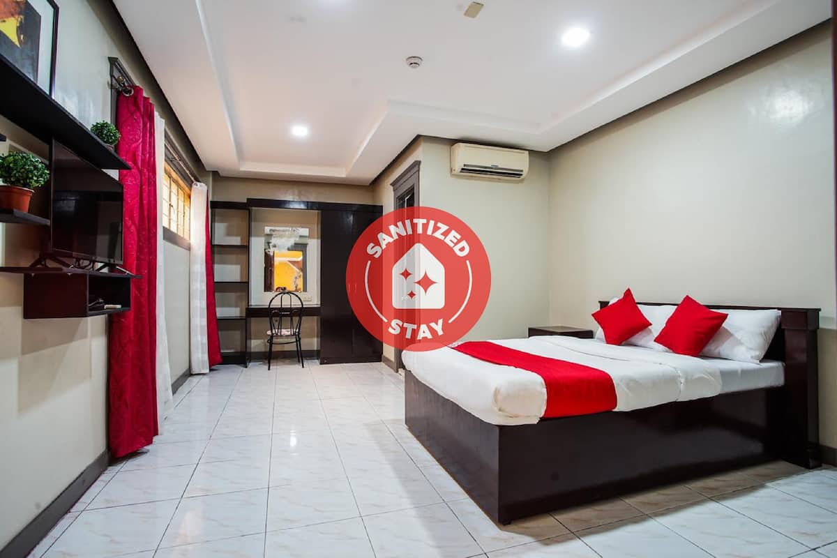 A hotel room with a bed, a desk, and a chair. There is a sign indicating the room is sanitized.