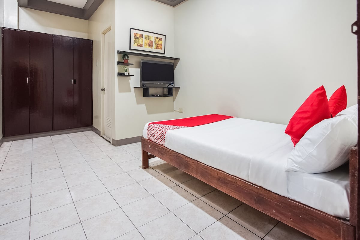 A bedroom with a bed, a wardrobe, a TV, and a framed picture on the wall.