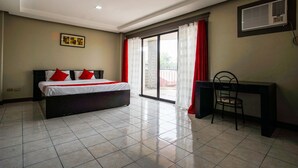A hotel room with a bed, a desk, and a sliding glass door leading to a balcony. - OYO 192 Tcc Condo - Hostel (Davao)