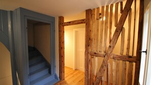 Un escalier dont les murs sont peints en bleu et dont les marches sont en bois, menant à une porte.