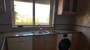A compact kitchen with a built-in dishwasher, a washing machine, and a double sink. - Cozy apartment in Guia (Guia)