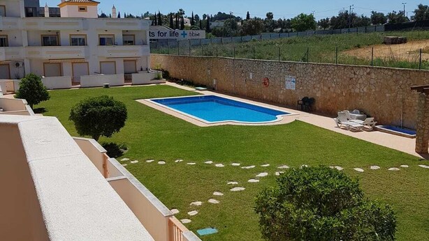 A residential area with a swimming pool, a stone wall, and a clear blue sky. - Cozy apartment in Guia (Guia)
