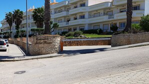 A multi-story hotel with balconies, palm trees, and a stone wall entrance. - Cozy apartment in Guia (Guia)