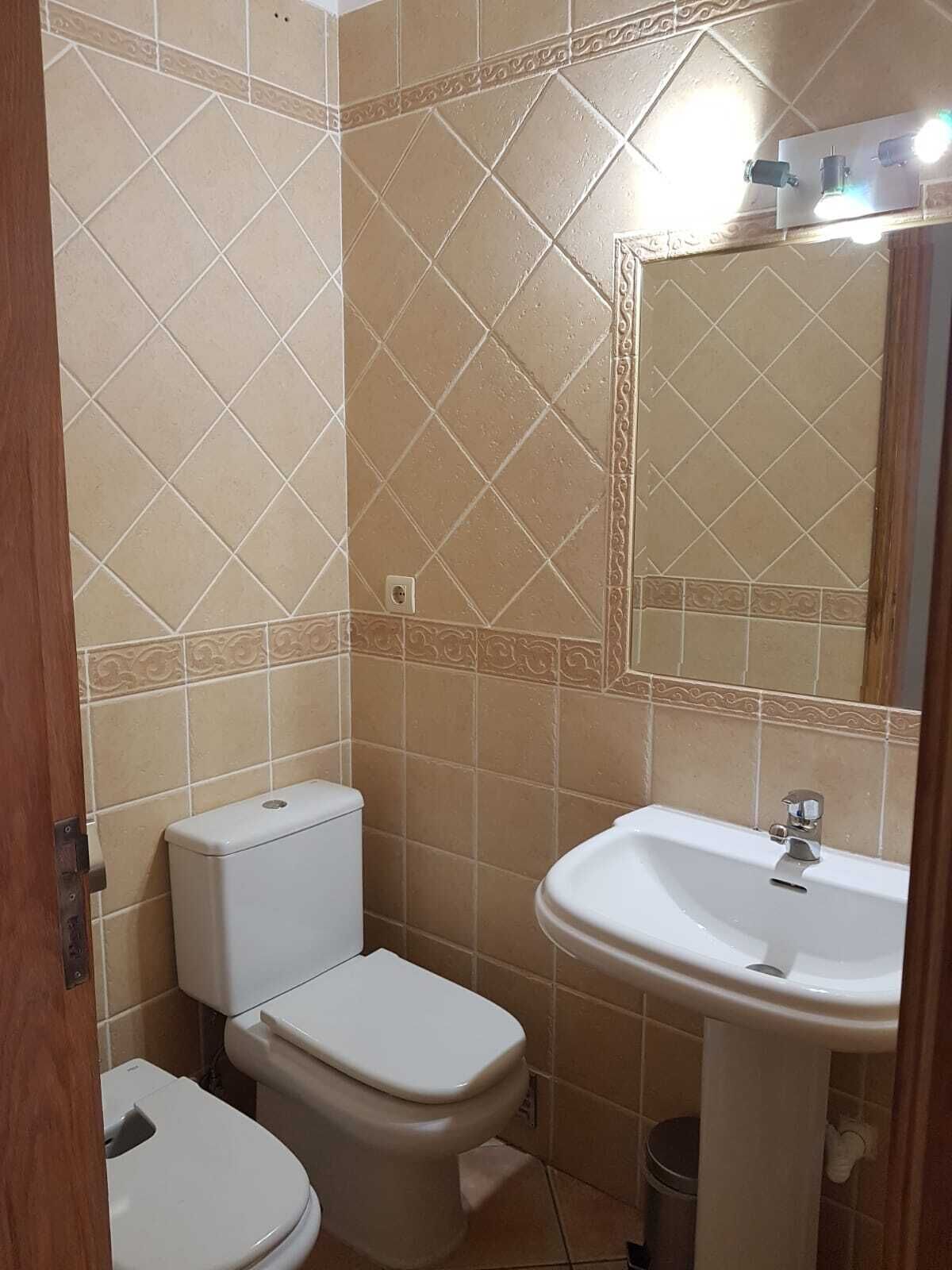 A bathroom with a toilet, sink, and mirror.