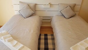 Two single beds with matching headboards, a small bedside table, and a checkered rug. - Cozy apartment in Guia (Guia)