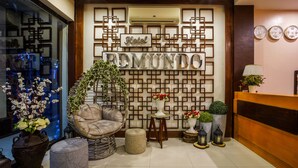 A reception area with a 'Hotel Remundo' sign, a wicker chair, a potted plant, and a reception desk.