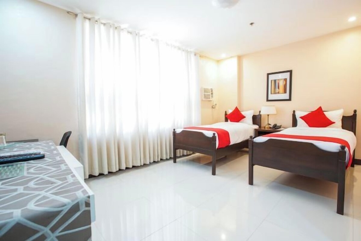 Une chambre d’hôtel avec deux lits, un bureau et une chaise.