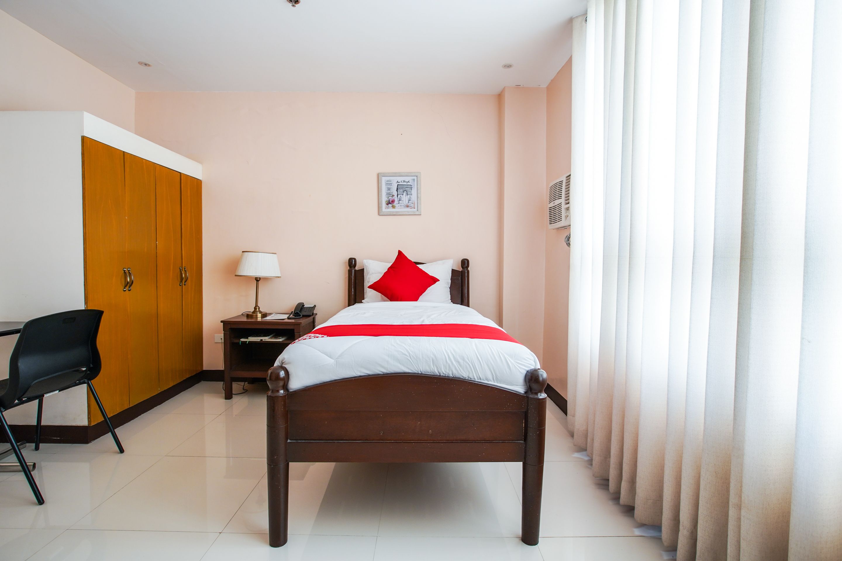 A neatly arranged bedroom with a wooden bed, a bedside table with a lamp, a chair, and a wardrobe.