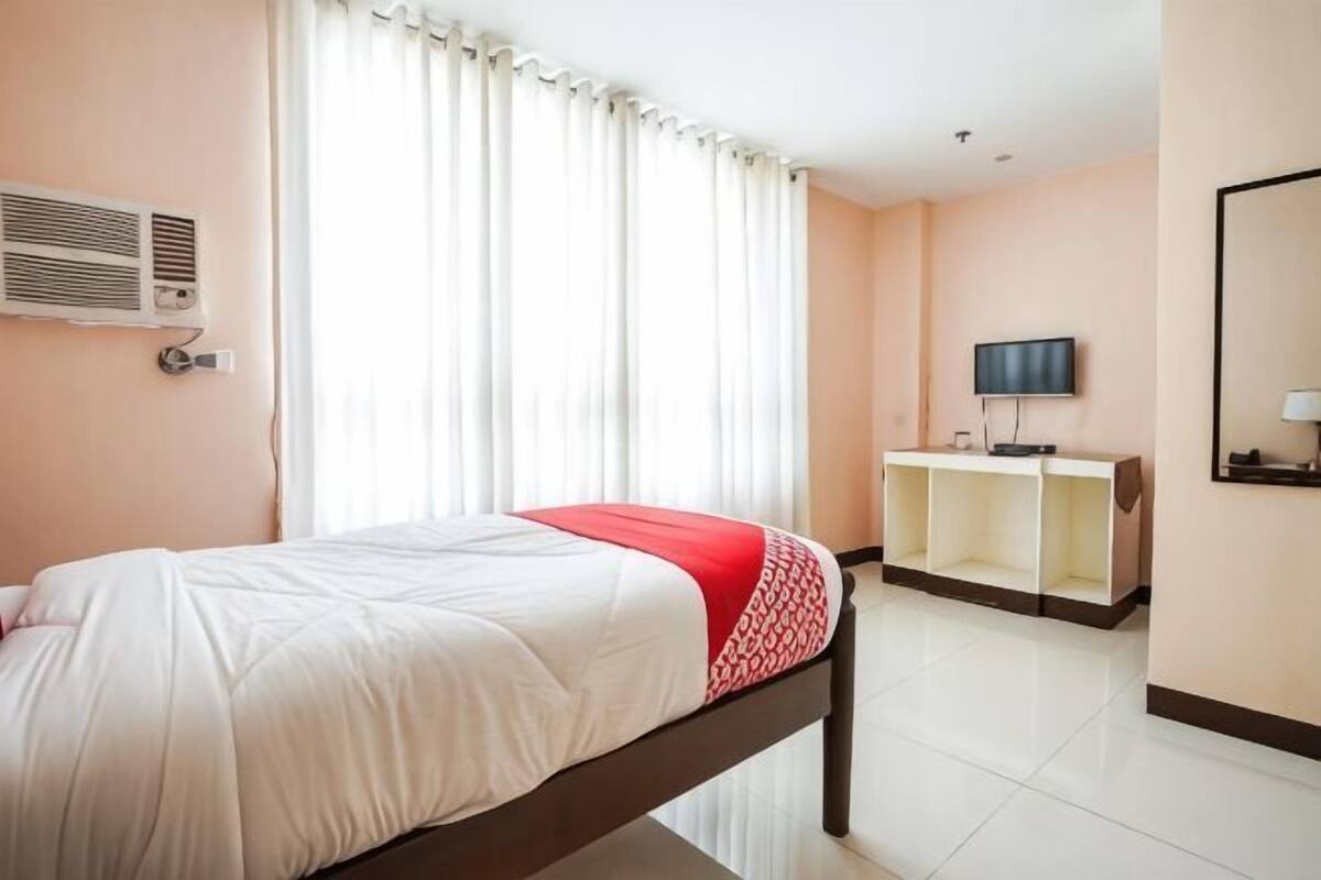 Une chambre d’hôtel avec un lit, une télévision, un bureau et un miroir.