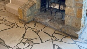 A stone fireplace with a fire, a staircase with white railings, and a patterned floor. - Beautiful architect house in the forest of Le Touquet (Le Touquet-Paris-Plage)