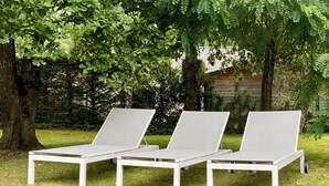 Three white lounge chairs with metal frames, positioned on a grassy area with trees in the background. - Beautiful architect house in the forest of Le Touquet (Le Touquet-Paris-Plage)