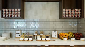 A kitchen counter with jars of food, a sign, and a basket of fruits.