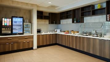 A modern kitchen with a refrigerator, microwave, and coffee machine.