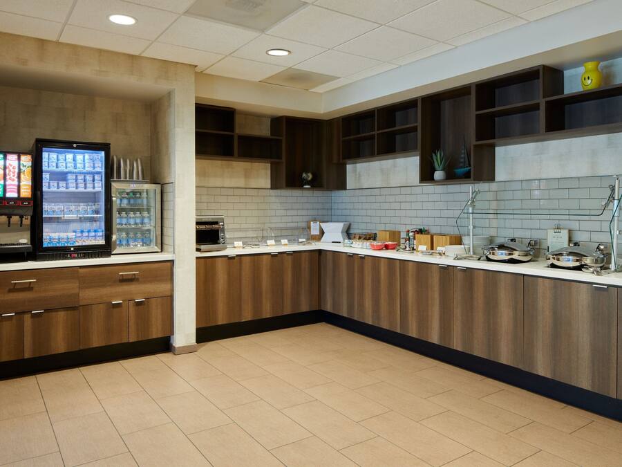 A modern kitchen with a refrigerator, microwave, and coffee machine.