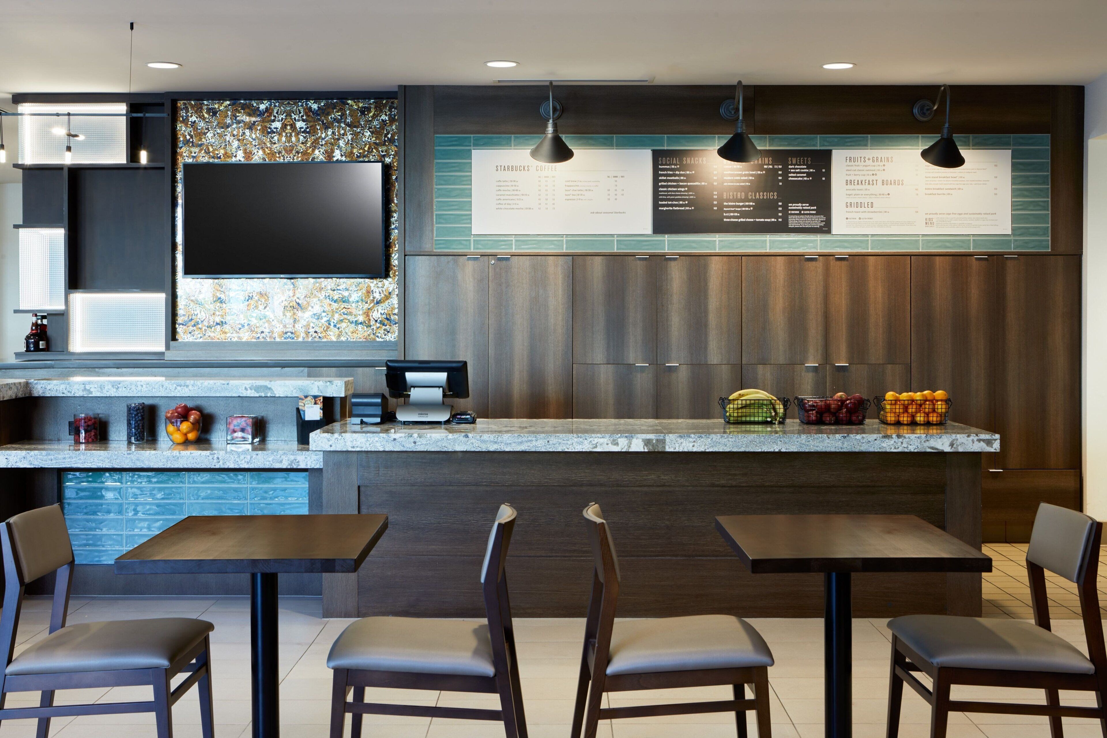 Un restaurante moderno con mostrador, tablero de menú y zona de estar.