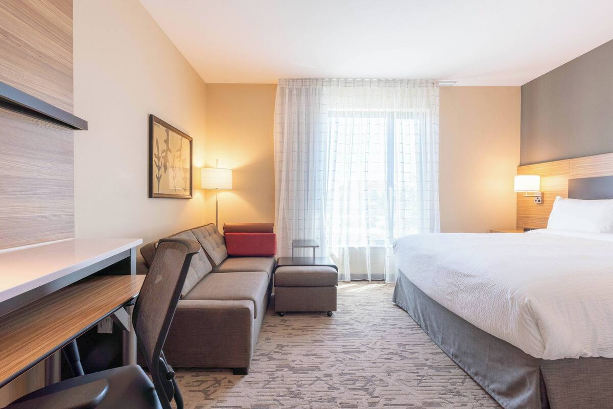 A hotel room with a bed, a sofa, a desk, and a chair.