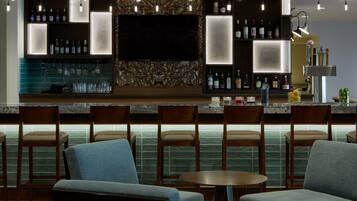 A bar area with a flat-screen TV, bar stools, and a variety of bottles and glasses.