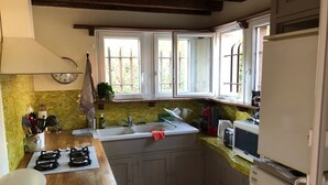 A kitchen with a gas stove, sink, and a microwave. There are cabinets and a window with a view of greenery outside. - Beautiful style house near the golf course (Soorts-Hossegor)