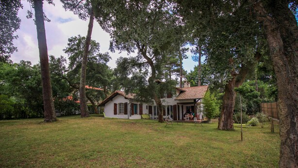 A house with a porch, surrounded by trees and a grassy yard. - Beautiful style house near the golf course (Soorts-Hossegor)