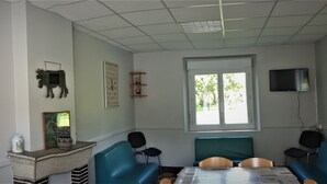 Een kamer met prikbord, open haard, televisie en zitplaatsen.
