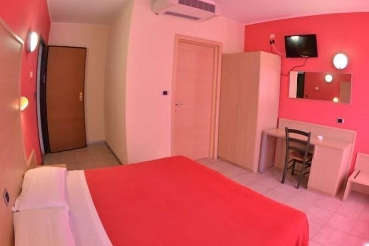 A room with a bed, a desk, a chair, a wardrobe, a television, and a mirror.