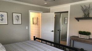 Una camera da letto con un letto, una porta, uno specchio e uno scaffale con piante.