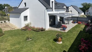 Een modern huis met een schuin dak, een overdekte patio en een verzorgd gazon.