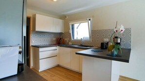 Een kleine keuken met witte kasten, een zwart aanrecht en een raam dat voor natuurlijk licht zorgt.