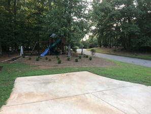 Relax and play in a tranquil outdoor space with a patio, playground, and lush greenery.